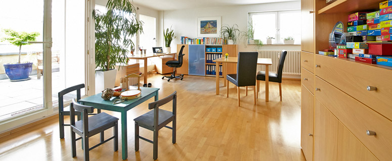 Großer, heller Therapieraum, mit Tisch für Erwachsene und Kindertisch mit Instrumenten